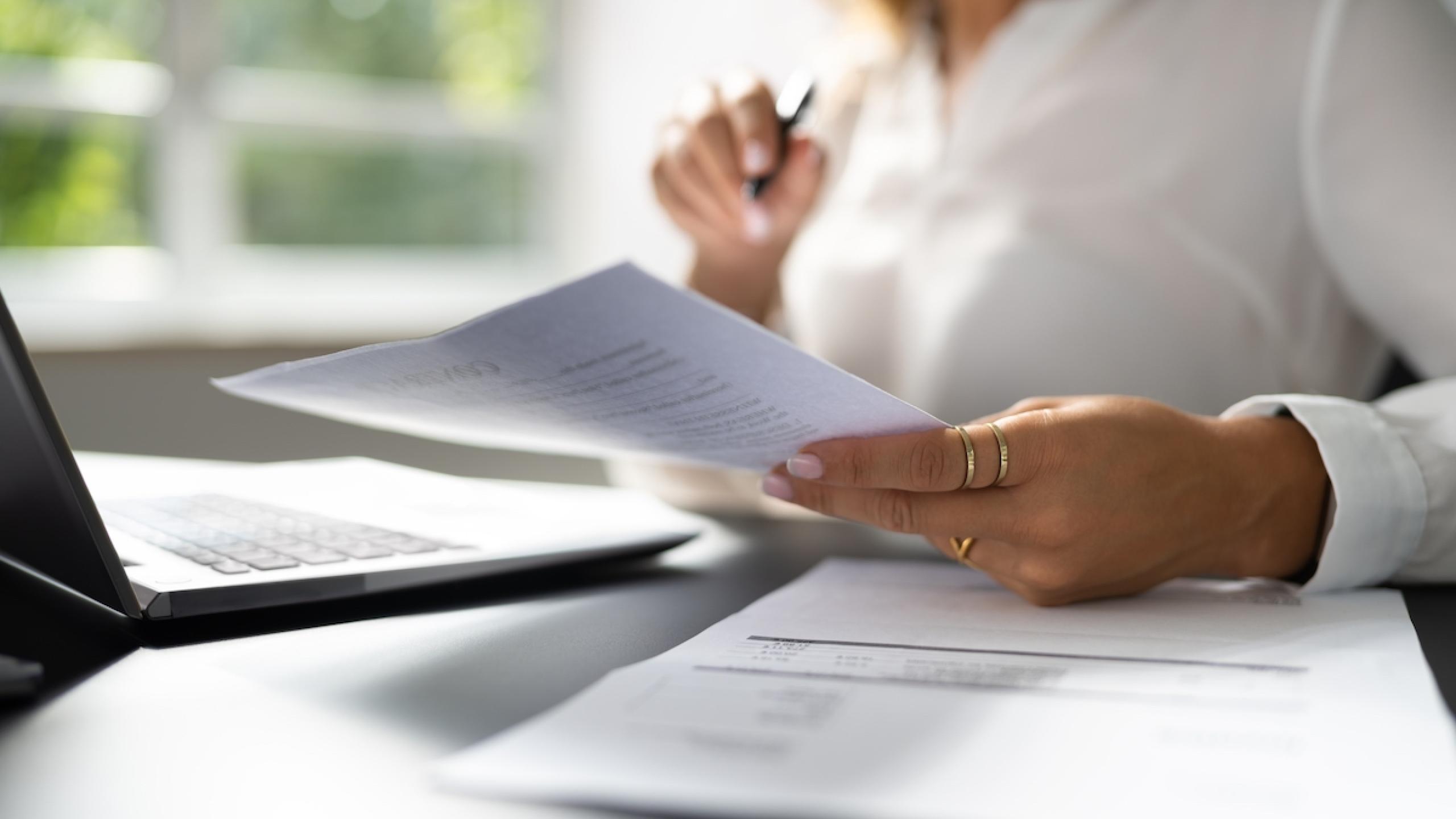 Close-up handen van vrouw die brief vasthoudt aan bureau.